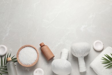 Photo of Flat lay composition with herbal massage bags and other spa products on light grey marble table. Space for text