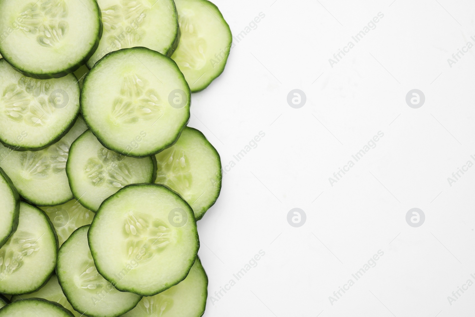 Photo of Fresh slices of cucumbers on white background, top view. Space for text