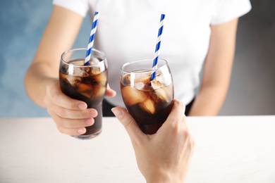 Photo of Friends with glasses of tasty refreshing cola at table, closeup view