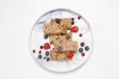 Tasty granola bars and berries on white background, top view