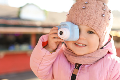 Little photographer taking picture with toy camera outdoors