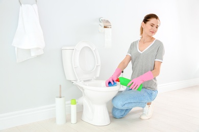 Woman cleaning toilet bowl in bathroom