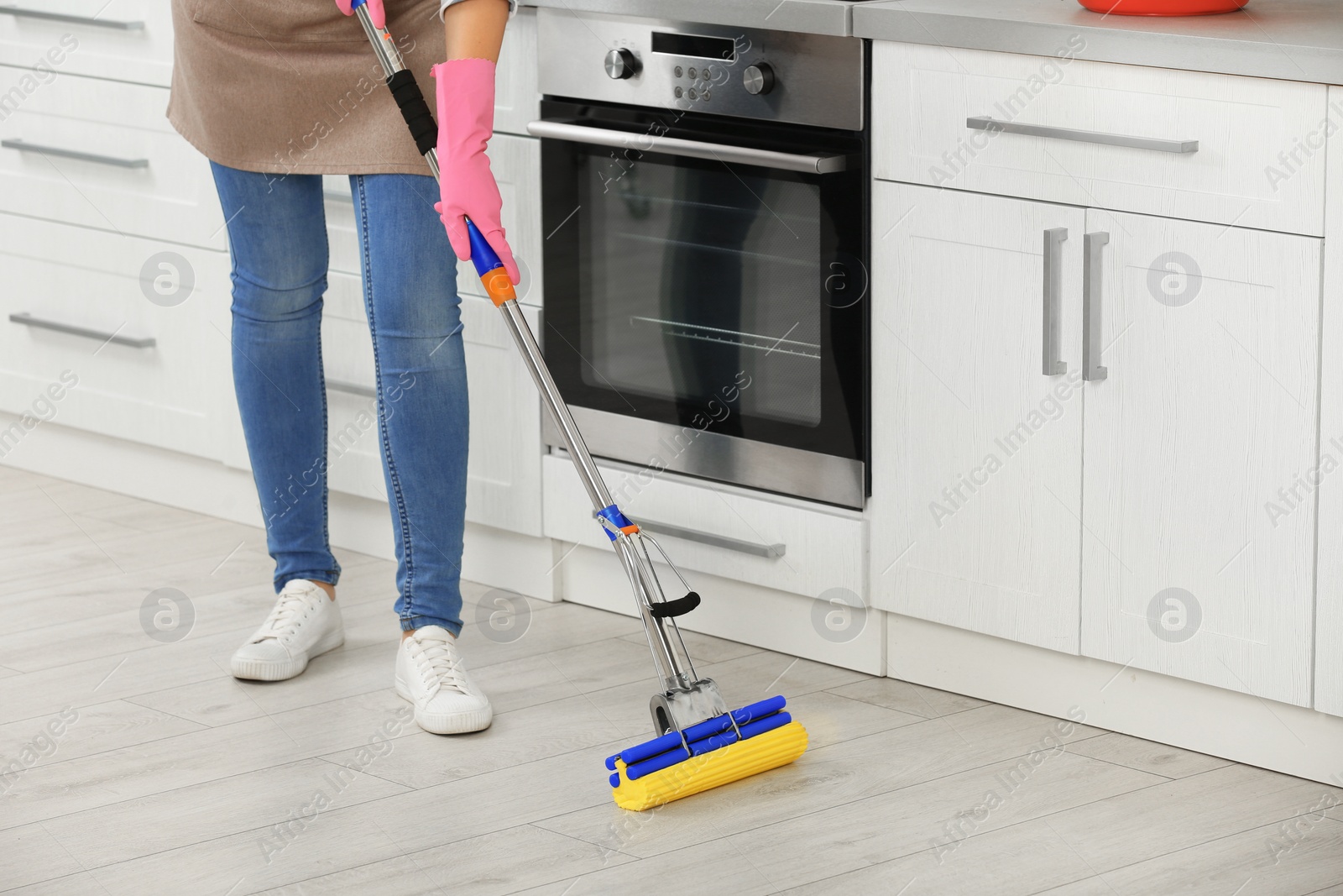 Photo of Woman cleaning floor with mop in kitchen