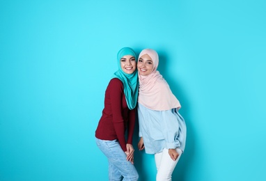 Photo of Portrait of young Muslim women in hijabs against color background