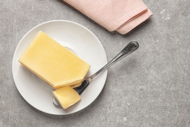 Photo of Plate with fresh butter and knife on table, top view. Space for text