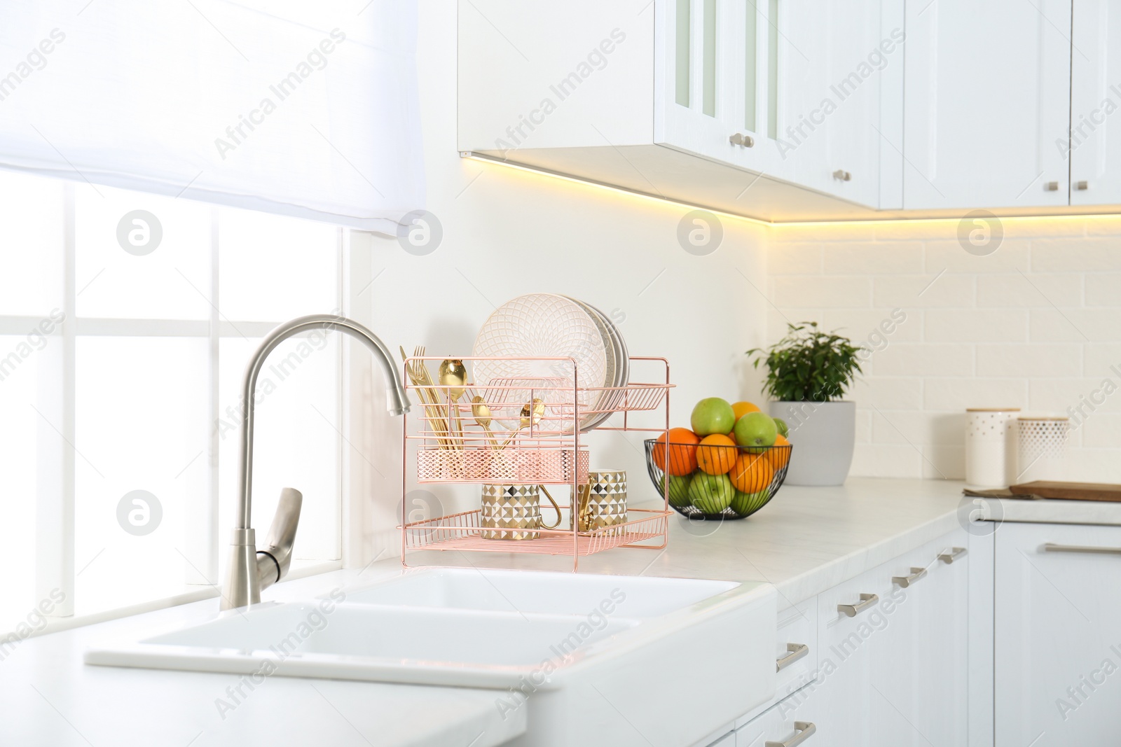 Photo of Clean dishes on drying rack in modern kitchen interior