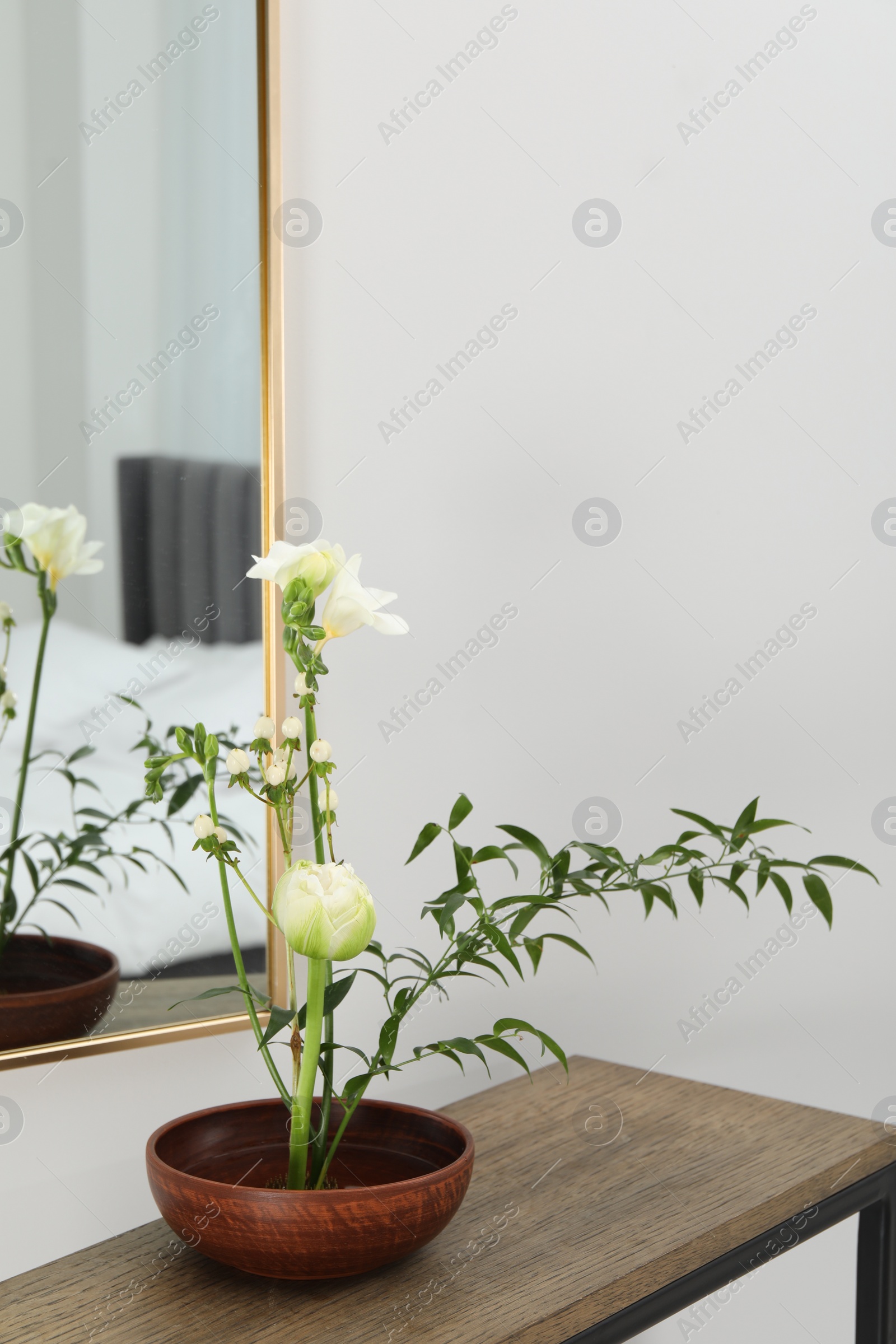 Photo of Stylish ikebana with beautiful flowers and green branch carrying cozy atmosphere at home