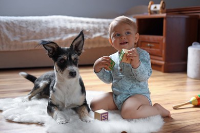 Adorable baby with toys and cute dog on faux fur rug at home