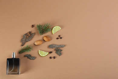 Flat lay composition with bottle of perfume on light brown background, space for text