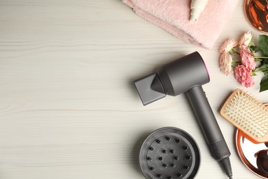 Photo of Flat lay composition with hair dryer and brush on white wooden table, space for text