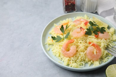 Photo of Delicious risotto with shrimps, lime and parsley on light grey table. Space for text