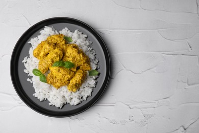 Photo of Delicious rice and chicken with curry sauce on white textured table, top view. Space for text