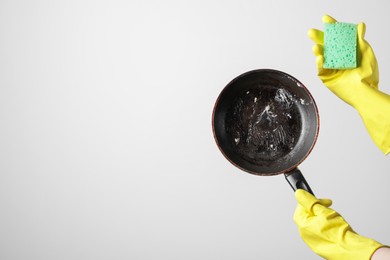 Photo of Woman holding dirty frying pan and sponge on white background, closeup. Space for text