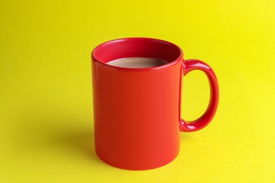 Photo of Red mug of freshly brewed hot coffee on yellow background