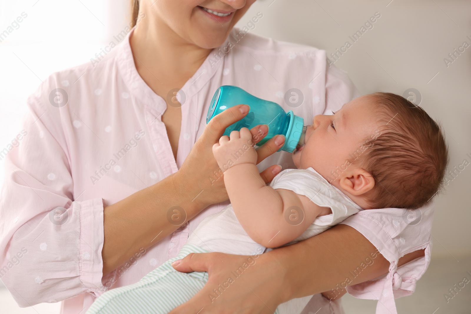 Photo of Mother feeding her cute child with infant formula indoors