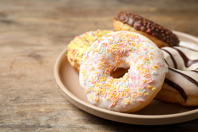 Delicious glazed donuts on wooden table, closeup