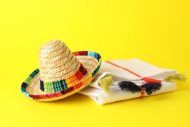 Mexican sombrero hat and poncho on yellow background