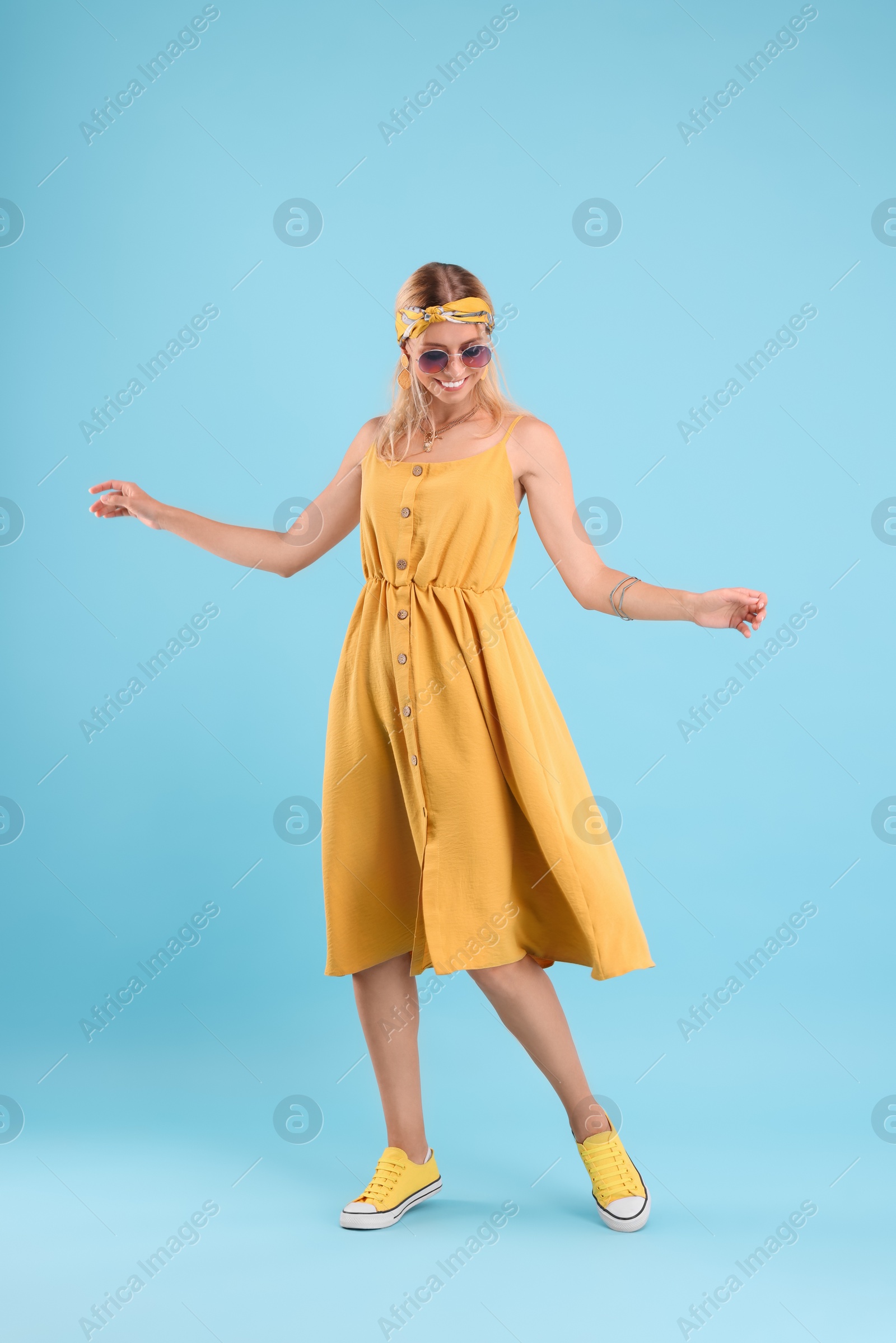 Photo of Portrait of smiling hippie woman dancing on light blue background