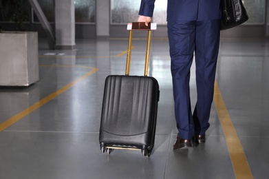 Photo of Businessman with black travel suitcase in airport