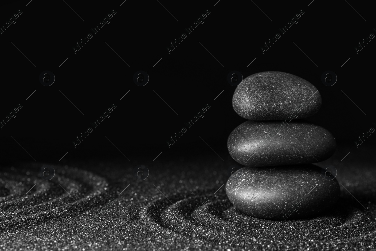 Photo of Black sand with stones and beautiful pattern against dark background. Zen concept