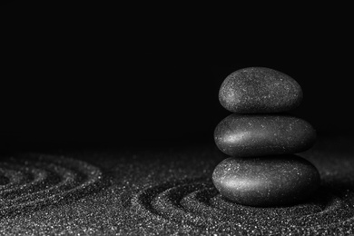 Photo of Black sand with stones and beautiful pattern against dark background. Zen concept