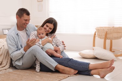Photo of Happy family with their cute baby on floor in bedroom