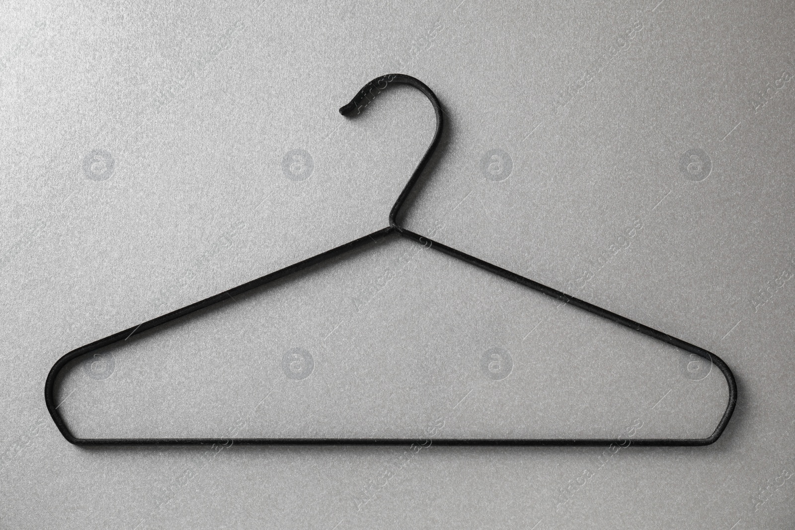 Photo of One black hanger on grey background, top view