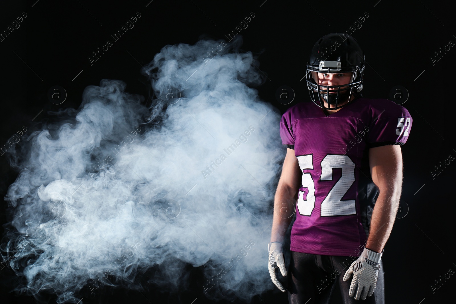 Photo of American football player wearing uniform on dark background. Space for text