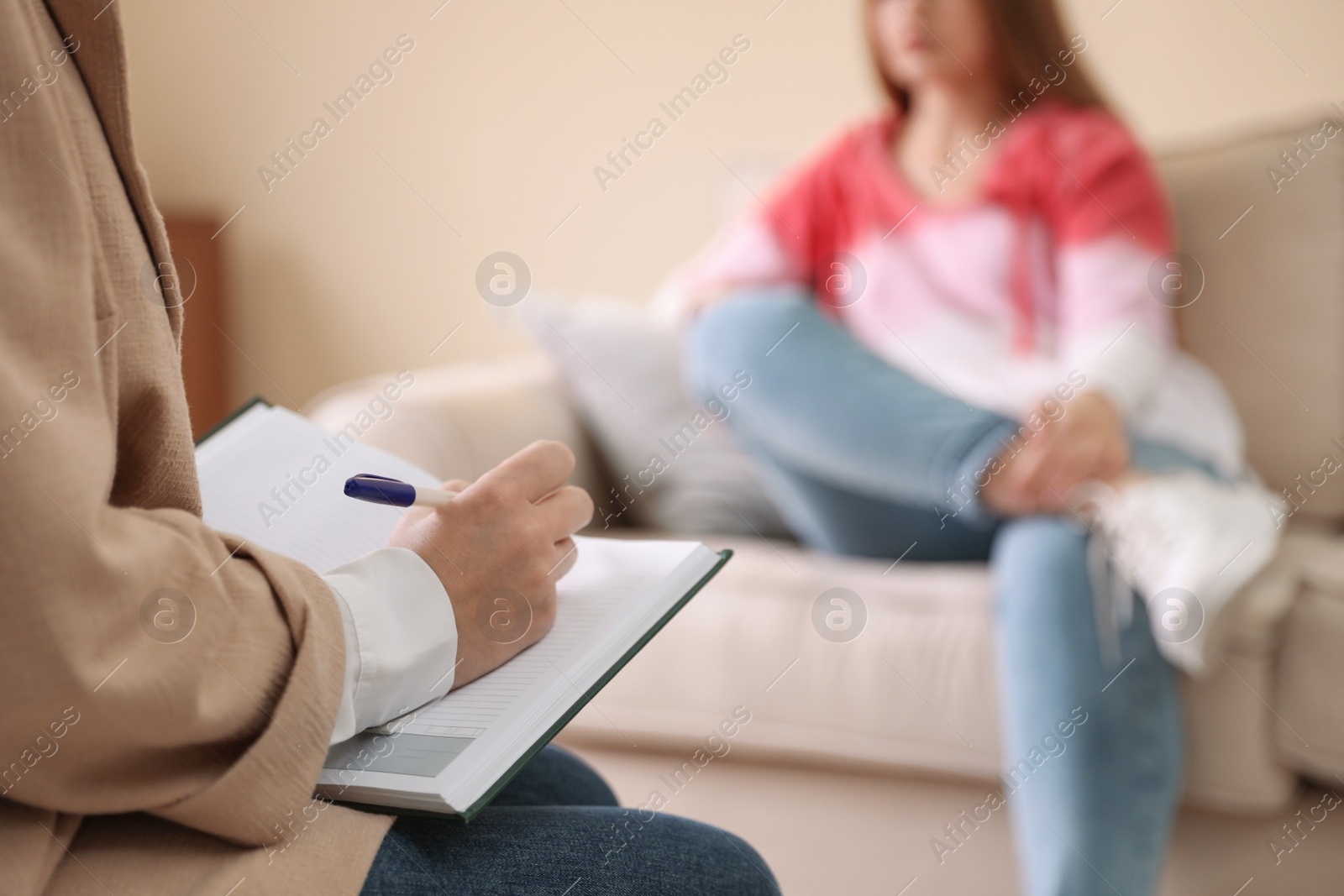 Photo of Professional psychotherapist and patient in office, focus on hands with notebook