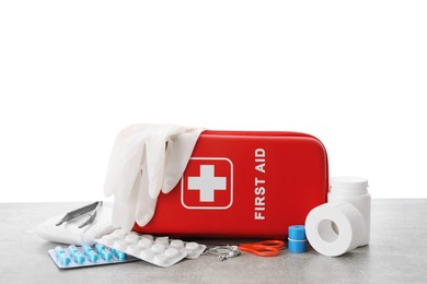 Photo of First aid kit, scissors, gloves, pills, plastic forceps and elastic bandage on light grey table against white background