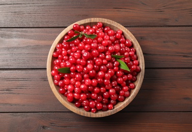 Photo of Tasty ripe cranberries on brown wooden table, top view