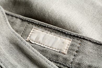 Photo of Blank clothing label on grey jeans, closeup