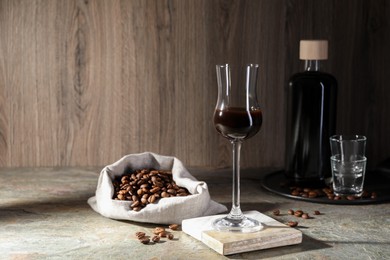Coffee liqueur and beans on textured table. Space for text