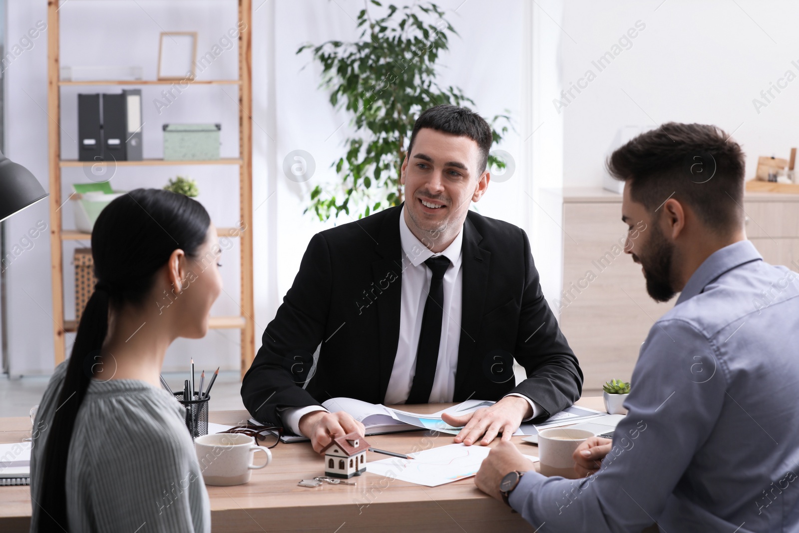 Photo of Real estate agent working with young couple in office. Mortgage concept