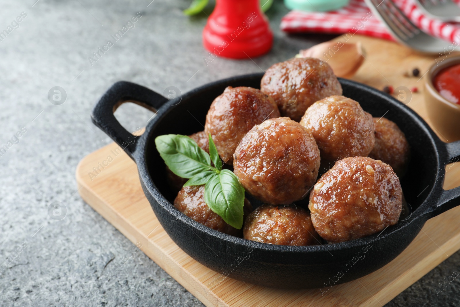 Photo of Tasty cooked meatballs with basil on grey table