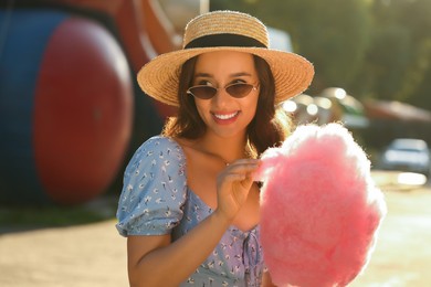 Photo of Beautiful young woman with cotton candy outdoors on sunny day
