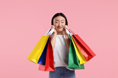 Photo of Happy woman with shopping bags on pink background