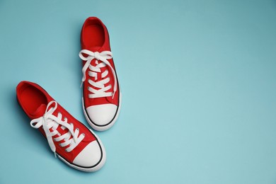 Photo of Pair of red classic old school sneakers on light blue background, flat lay. Space for text