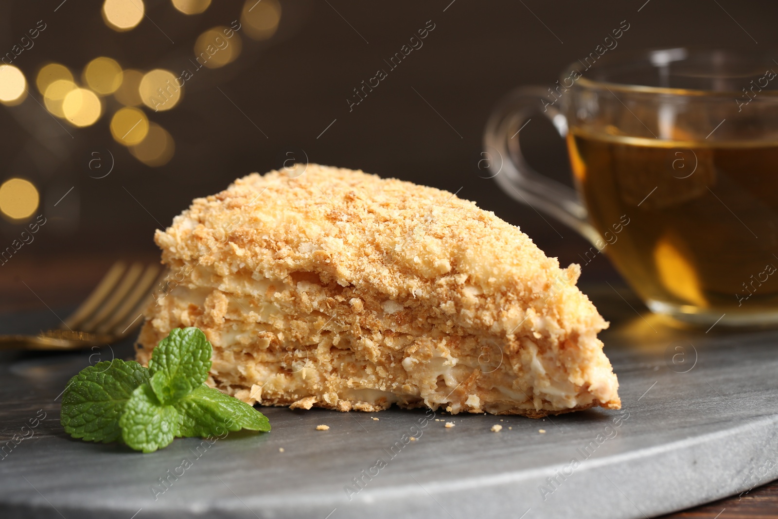 Photo of Piece of delicious Napoleon cake served on table, closeup