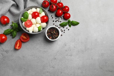 Photo of Delicious mozzarella balls, tomatoes and basil leaves on light gray table, flat lay. Space for text