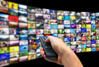 Image of Streaming video services. Man using remote control to change channels on TV, closeup