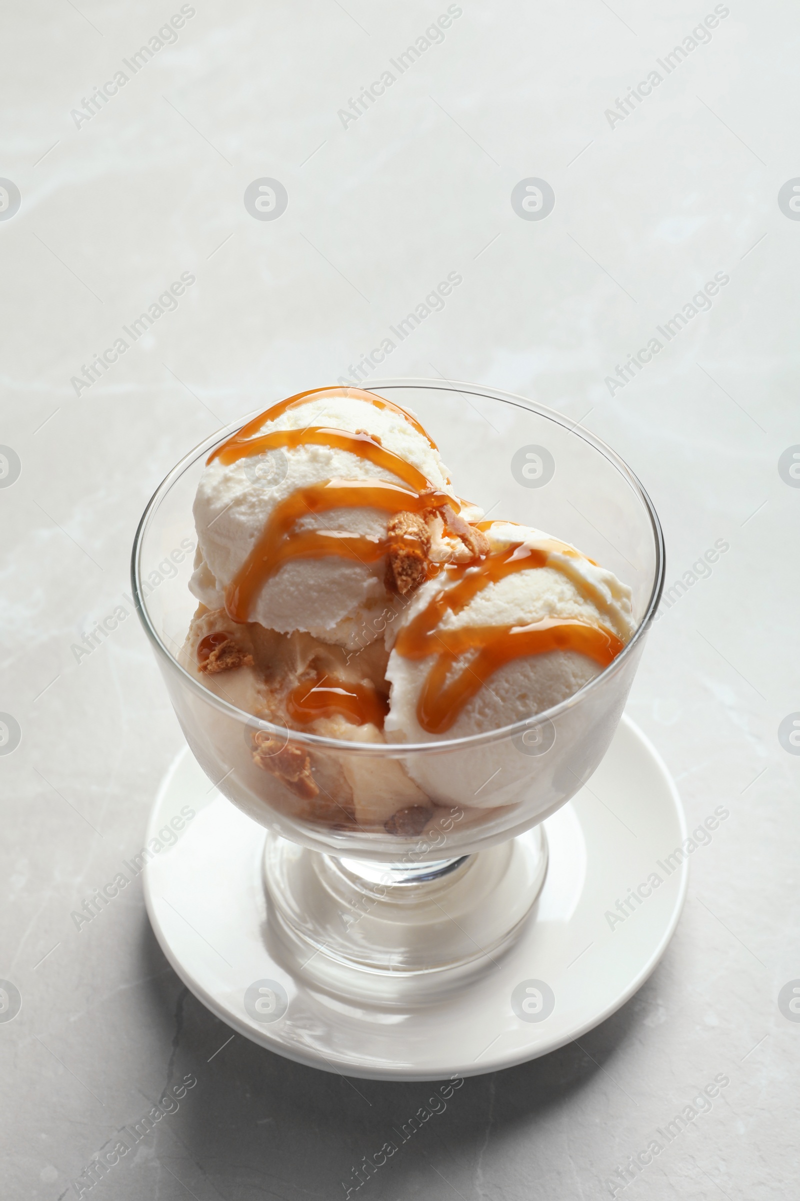 Photo of Bowl with caramel ice cream on light background