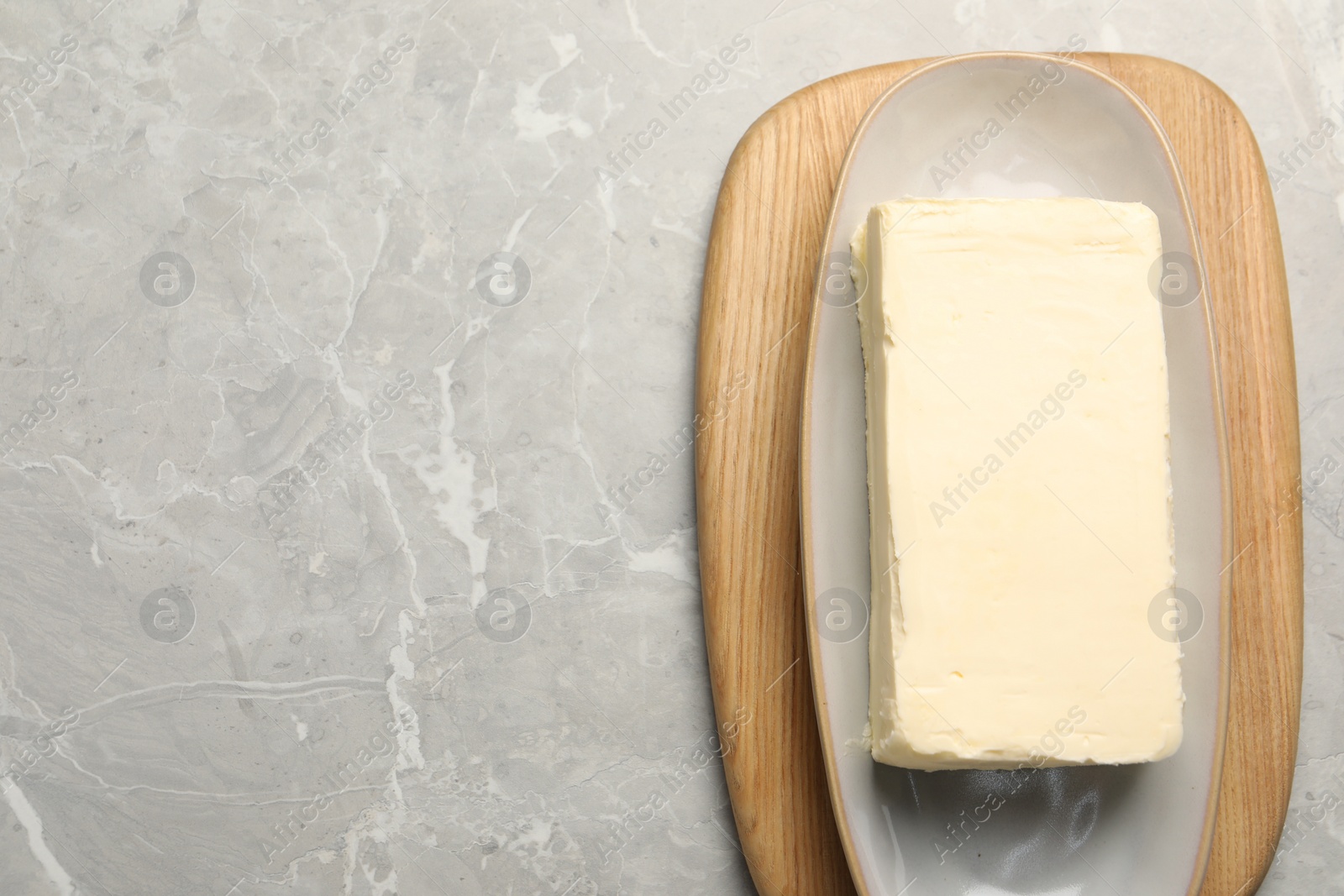 Photo of Block of tasty butter on grey table, top view. Space for text