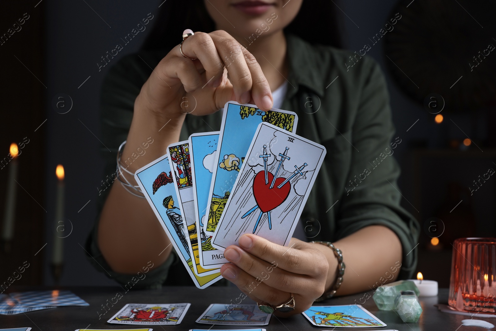 Photo of Fortune teller with tarot cards at grey table indoors, closeup