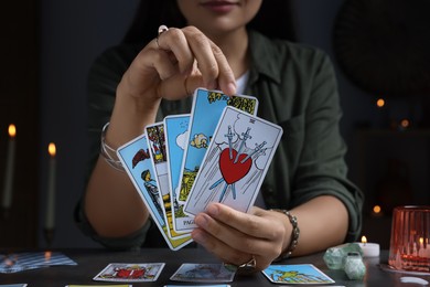 Fortune teller with tarot cards at grey table indoors, closeup