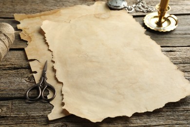 Photo of Sheet of old parchment paper, scissors and pocket chain clock on wooden table