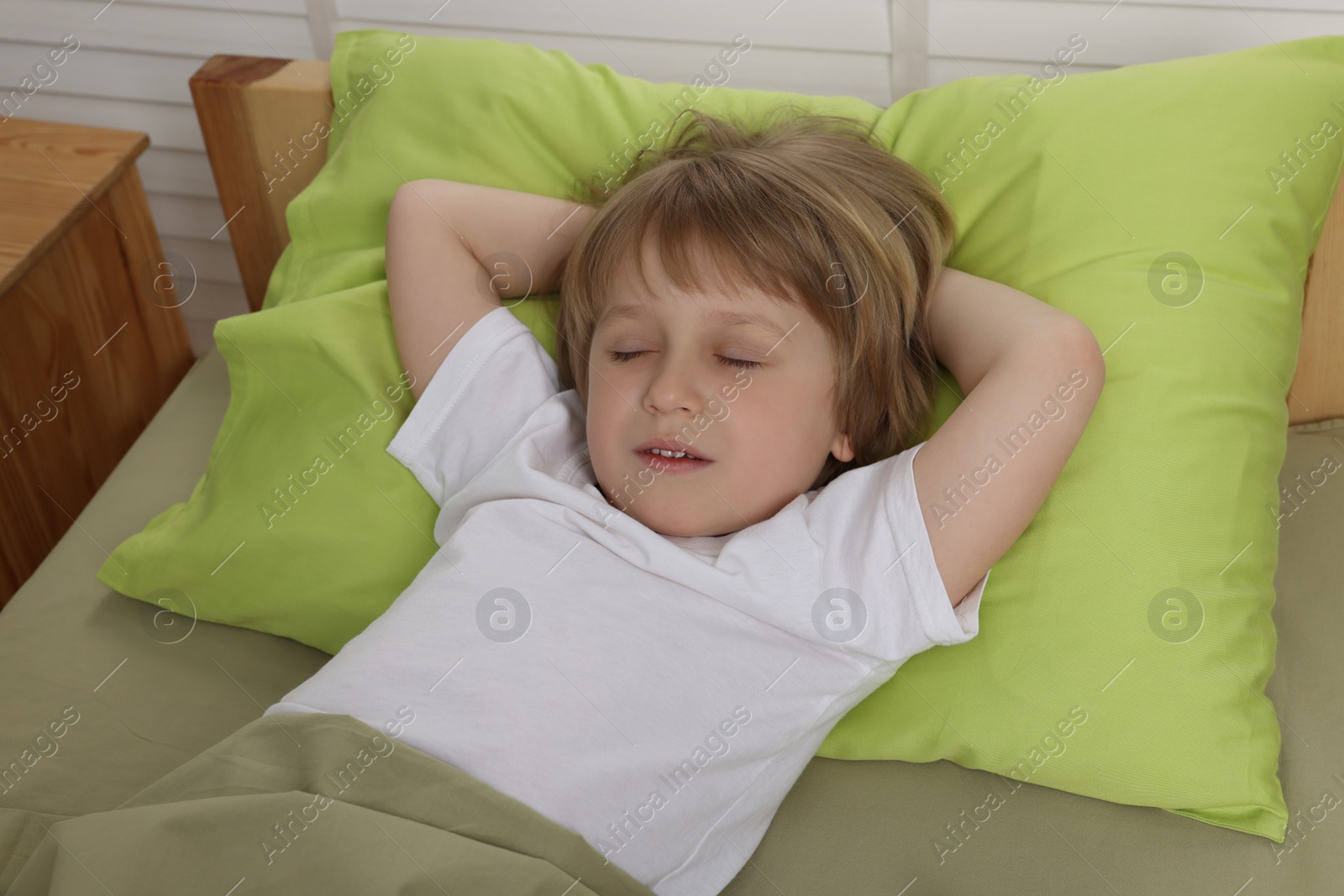 Photo of Little boy snoring while sleeping in bed indoors