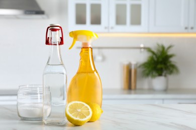 Vinegar, baking soda and lemon on white marble table in kitchen, space for text. Eco friendly natural detergents