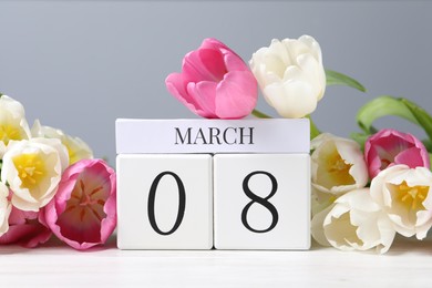 Photo of International Women's day - 8th of March. Wooden block calendar and beautiful flowers on white table