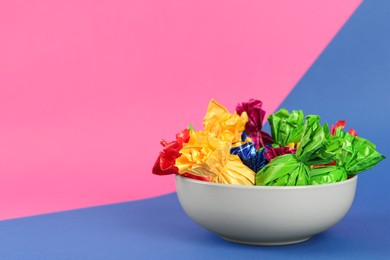 Candies in different wrappers on color background, space for text